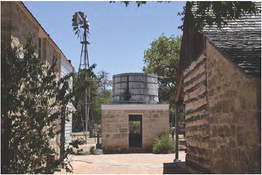 The Sauer-Beckmann farm houses a vintage windmill and tank house pictured between the historic buildings from the chicken and turkey coop behind the buildings. – Standard-Radio Post file photo