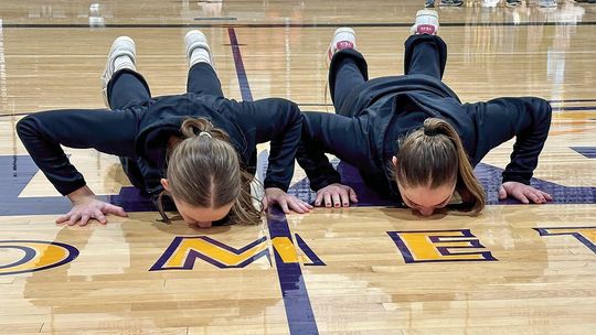 Leland girls basketball seniors Ella Seguin (left) and Mallory Lowe (right) kiss the Comets basketball court on senior night. Courtesy photo