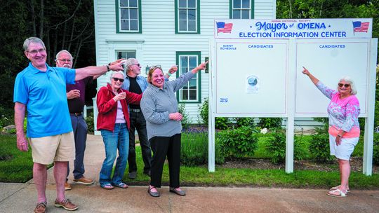 The Omena Historical Society launched its triennial Omena Mayor elections this past Monday. Pictured at the Election Center in front of the museum are, from left, Jeff Heitzman, Steve Stanton, Barb Grosmark, Harold McKee, Marsha Buehler, and Lauris Woolford. Photo by Mark Smith