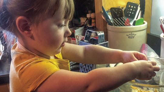 This wee one helps out her grandmother in the kitchen breaking up cheese for macaroni and cheese