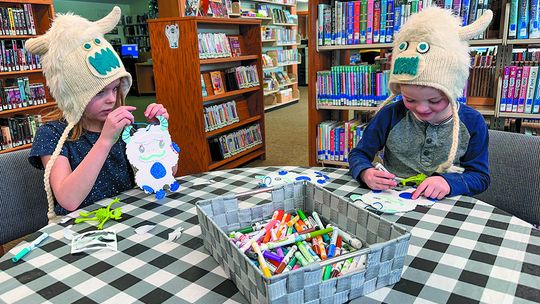 Two siblings wearing yeti hats that their grandparents got them while enjoying the activities at the Suttons Bay-Bingham Township library. Enterprise photo by Amy Hubbell
