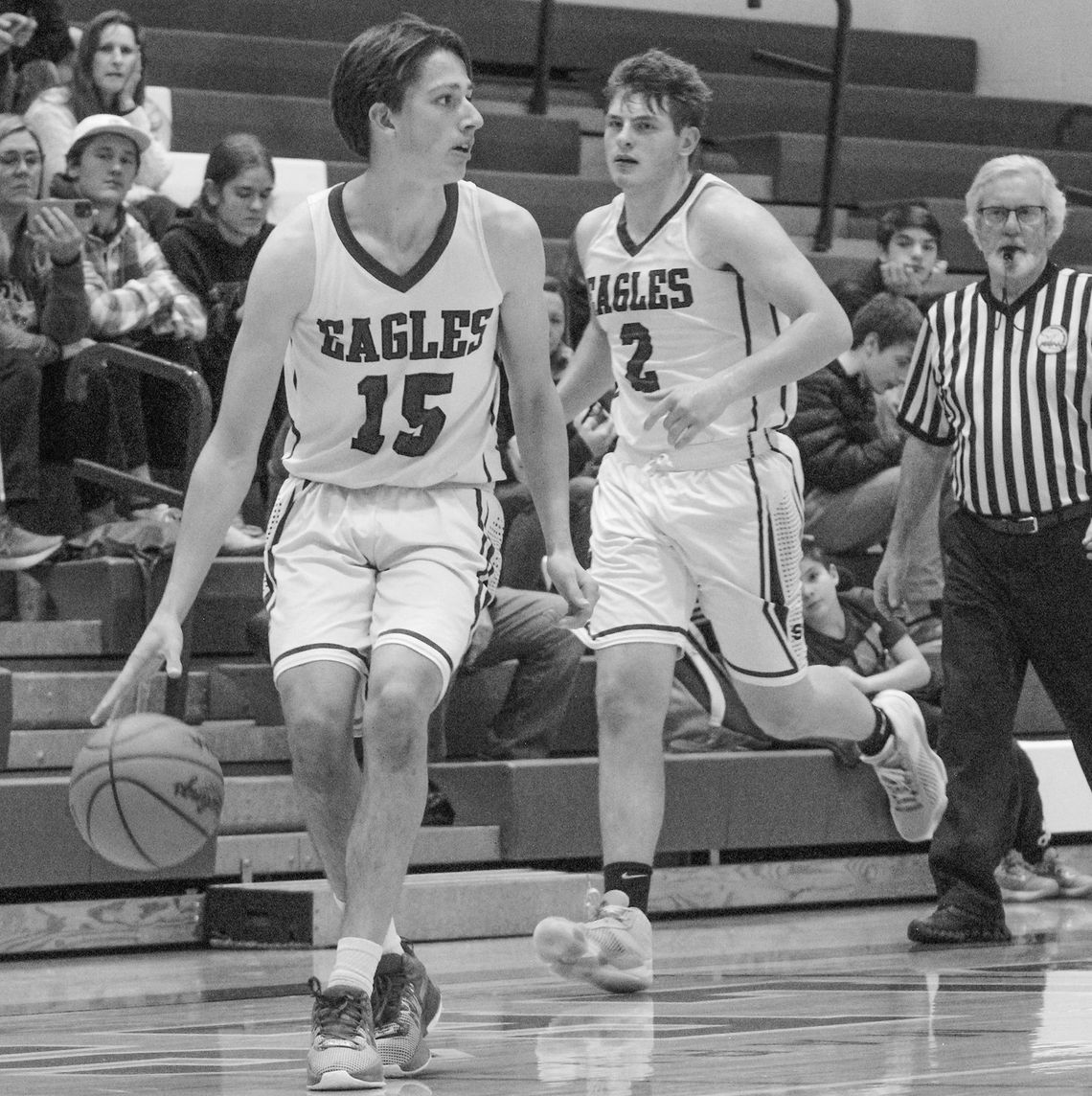 Lake Leelanau St. Mary sophomore Oliver Mitchell dribbles up the court during a home game against Grand Traverse Academy on Tuesday while Eagle senior Jerry Schaub hustles up the floor. Enterprise photo by Brian Freiberger