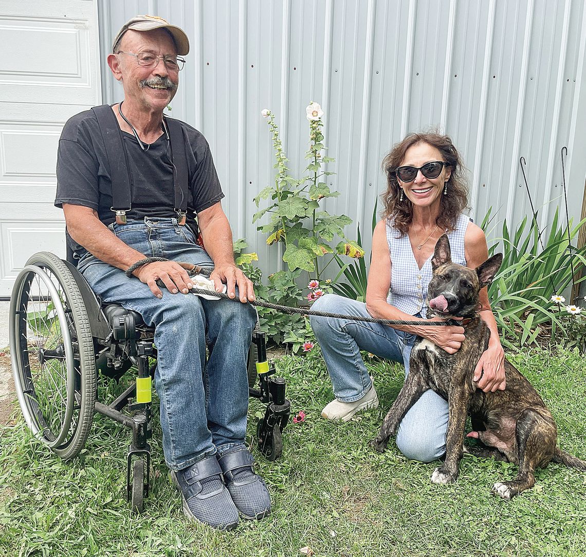 Gary Lowe (left) and Linda Gottwald (right) play with Hawthorne at the Great Lakes Humane Society near M-72. Enterprise photo by Brian Freiberger