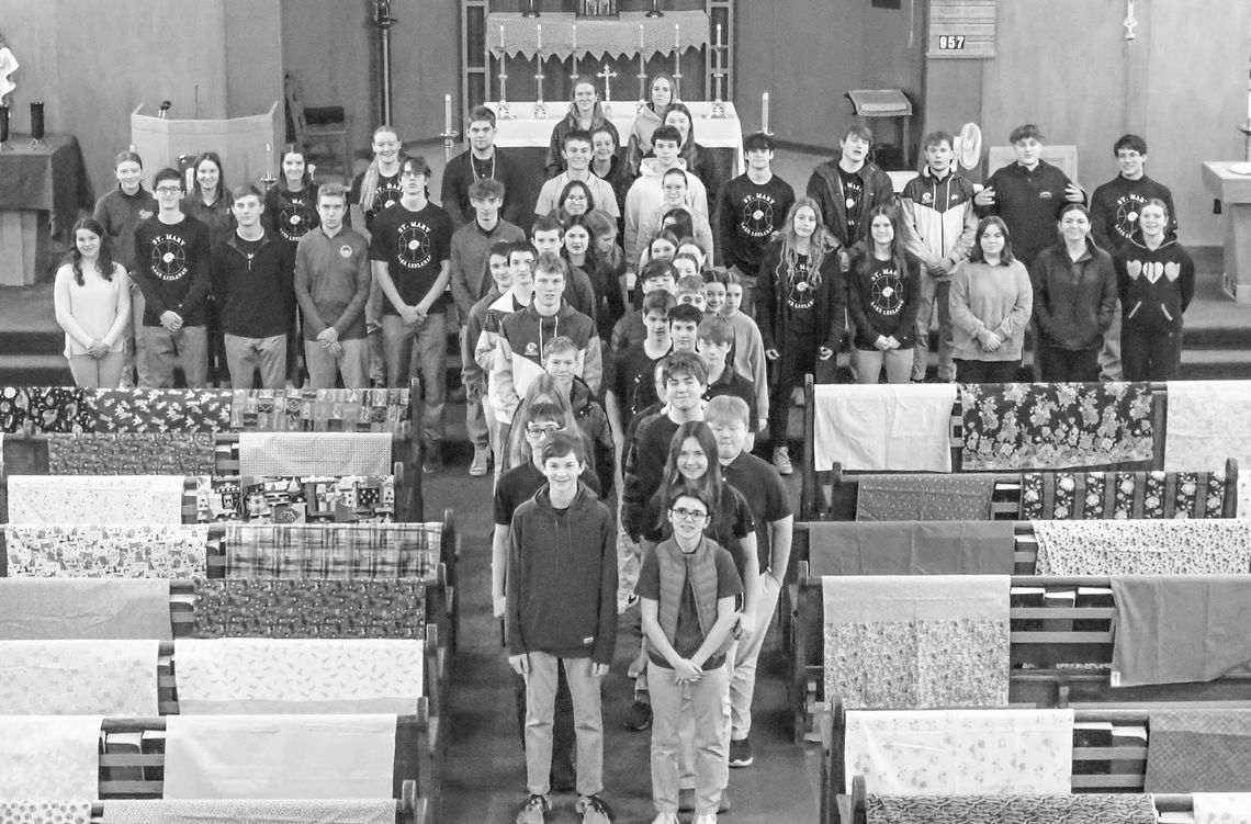 St. Mary School students from grades 8 through 12 pause for a blessing of blankets and dresses by Bishop Jeffrey Walsh, from the Diocese of Gaylord.