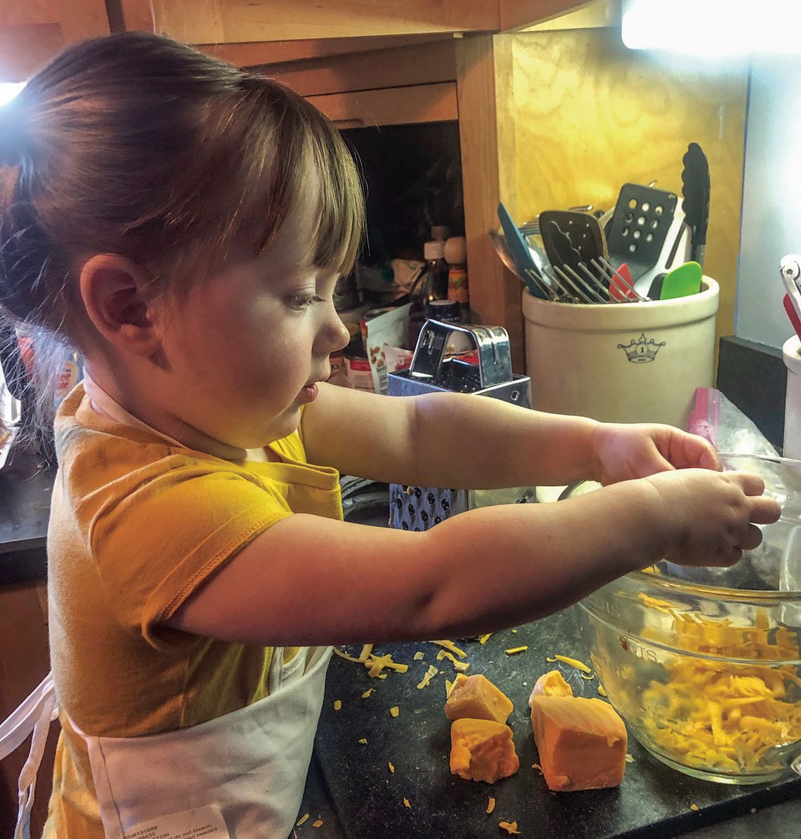 This wee one helps out her grandmother in the kitchen breaking up cheese for macaroni and cheese